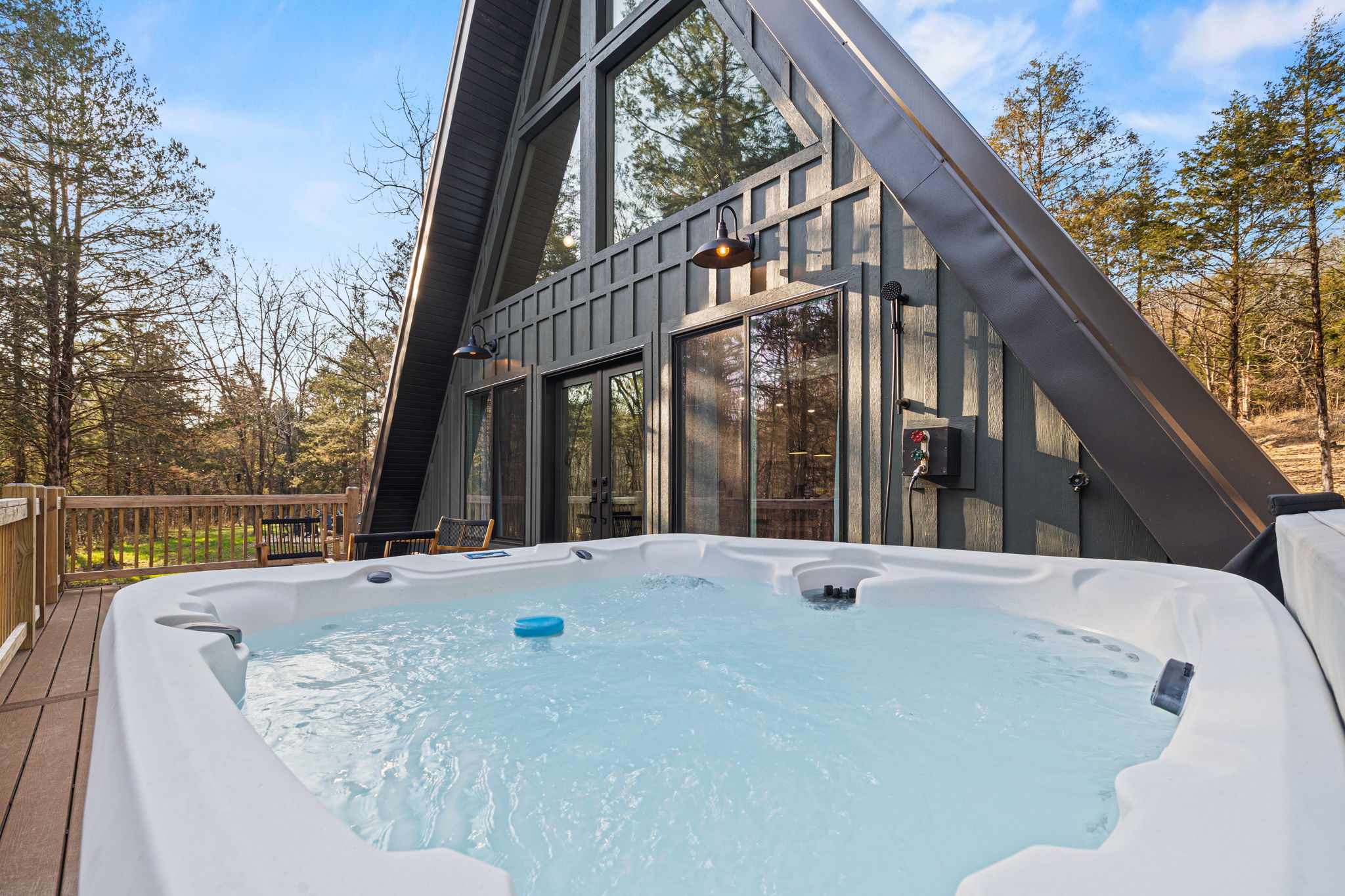 The hot tub on the deck with the A-frame cabin behind